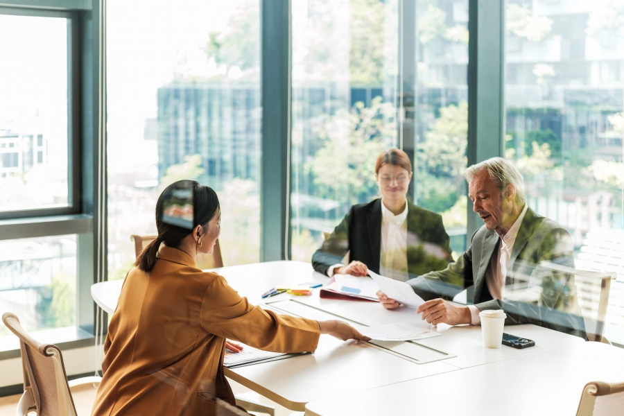 Team of professionals seated at a table, actively participating in a meeting within an office space.