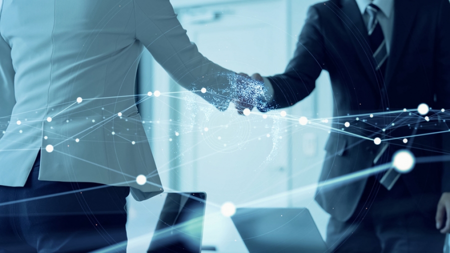 Two people engaging in a handshake over a network design, illustrating a successful telecoms recruitment connection.