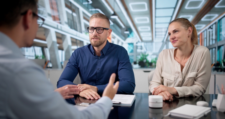 Three individuals engaged in conversation while seated at a table, displaying a friendly and interactive atmosphere.