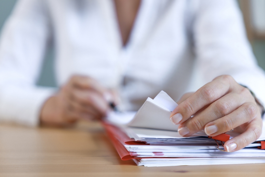 An individual is engaged in writing on a sheet of paper, demonstrating concentration.