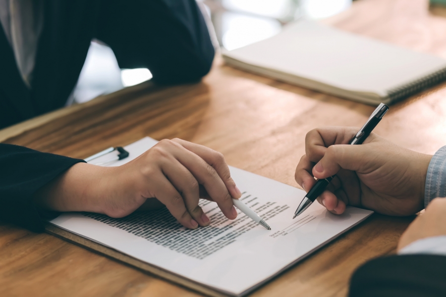 A man and woman in business attire signing a contract, indicating a formal partnership or agreement.